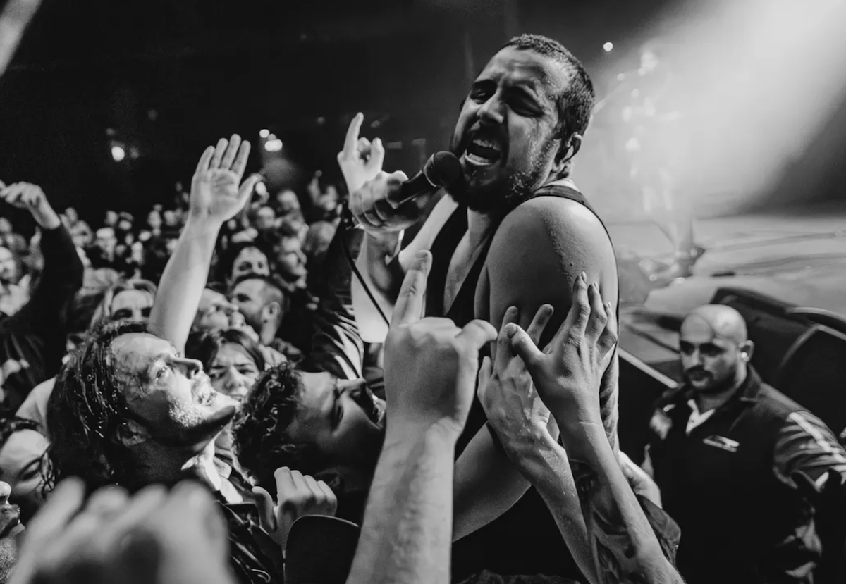 Adelaide rock band Bad//Dreems frontman performing passionately into a microphone while leaning directly into a crowded audience at a live gig.